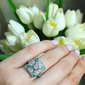 Round Brilliant Cut Diamond in a Victorian Style Setting with Emerald Accent Stones