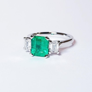 Three Stone Ring Featuring a Columbian Emerald and Two Emerald Cut Diamonds