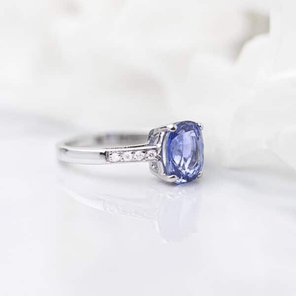 Light blue sapphire engagement ring with with diamonds adorning the white gold band.