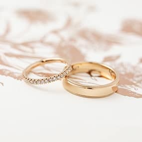 Rose gold handmade wedding rings with diamonds and milgrain detail, made by clients in a wedding ring experience.