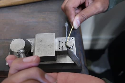 Couple learning to shape metal to make their own wedding rings at Larsen Jewellery
