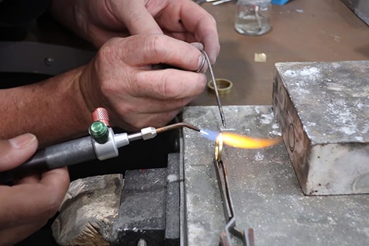 Jewellery helping a client to make their own wedding ring from gold