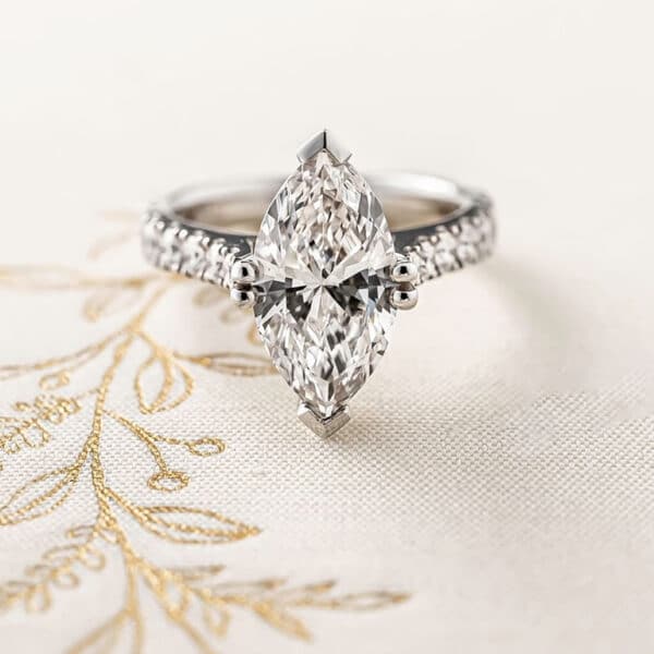 Marquise diamond engagement ring with diamonds adorning the shoulders.