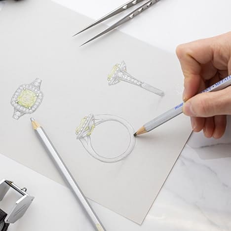 Jeweller sketches a bespoke engagement ring with a vivid yellow diamond in white gold with a halo.