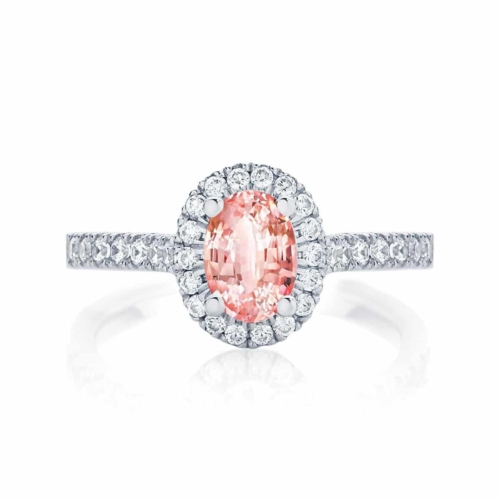 Peach sapphire engagement ring with a diamond halo and diamond band.