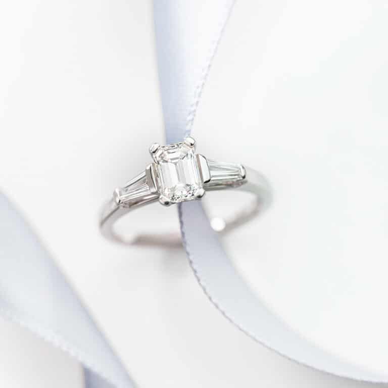 An Emerald Cut Diamond Ring Featuring Tapered Baguette Side Stones