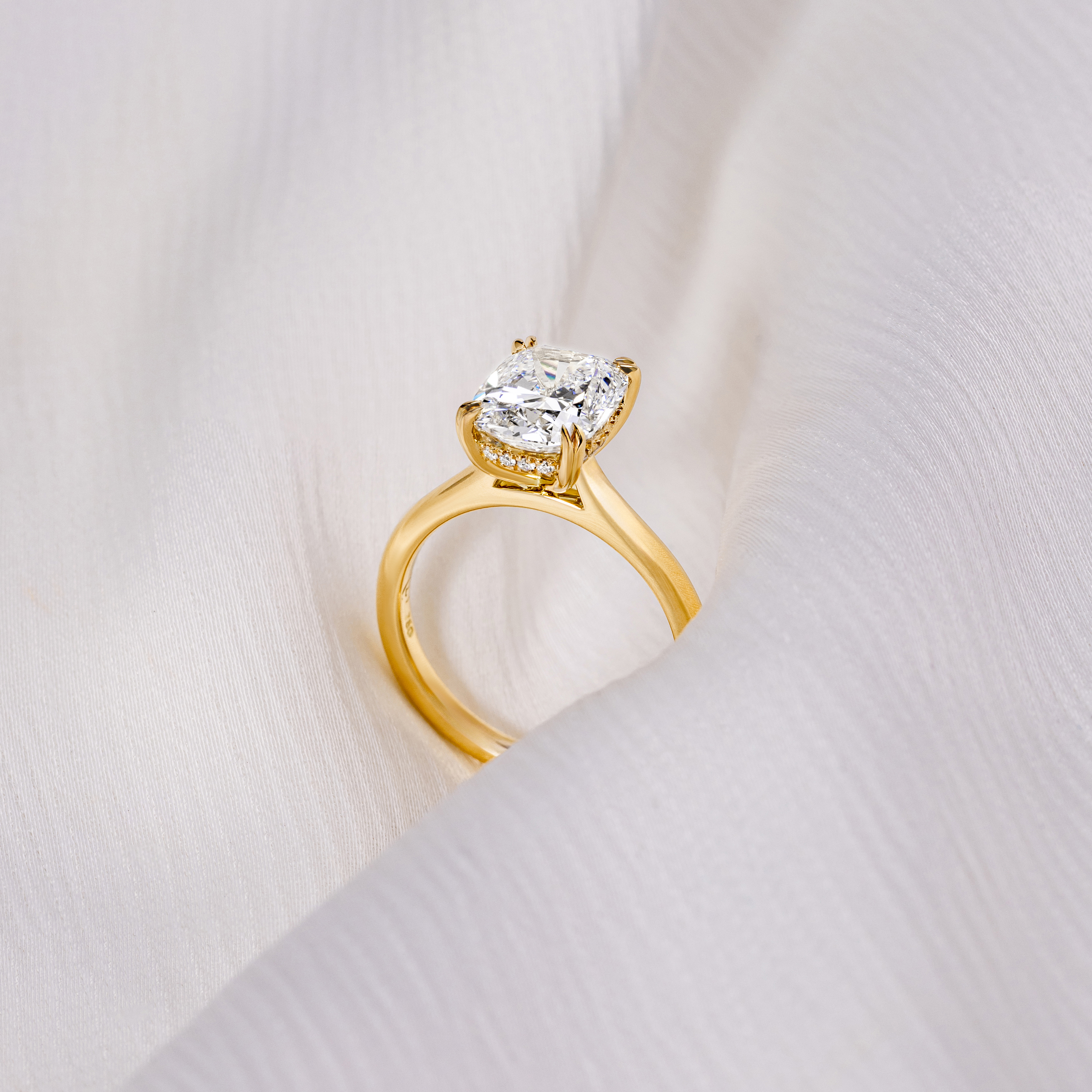 customer engagement ring with a yellow gold band and a emerald cut diamond centre stone with a diamond encrusted claw